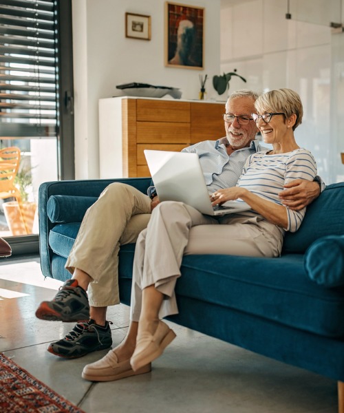 retired couple with laptop sitting on couch